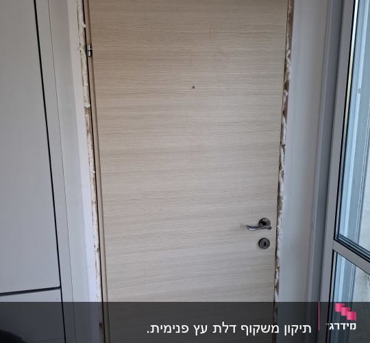 דלת עץ מותקנת עם ידית ומנעול